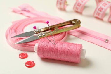 Pembe dikiş malzemeleri beyaz arkaplanda, yakın plan.