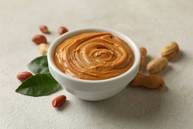 Fıstık ezmesi ve yapraklar ve beyaz arka planda fıstık ezmeli kase.