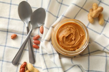 Peçeteyle fıstık ezmesi, kavanoz fıstık ezmesi ve kaşık.