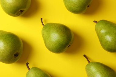 Sarı zemin üzerinde taze yeşil armutlar, üst görünüm