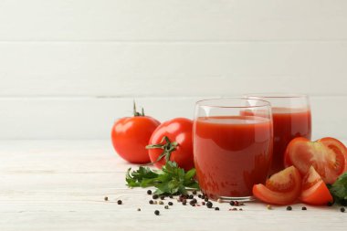 Domates suyu, domates ve baharatlı bardaklar ahşap arka planda.