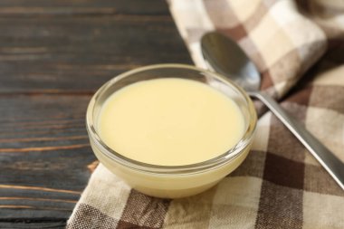 Havlu, kaşık ve kase, ahşap arka planda yoğunlaştırılmış süt.