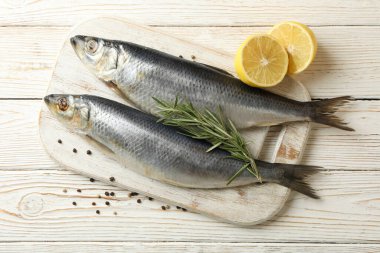 Beyaz ahşap arka planda taze ringa balığı ve baharatlı tahta.