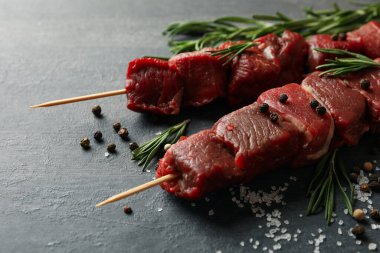 Koyu arka planda çiğ et ve baharatlı şişler.