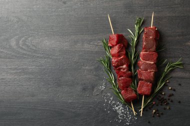 Koyu arka planda çiğ et ve baharatlı şişler.