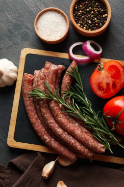 Koyu arka planda çiğ sosis, bitki ve baharatlı pano