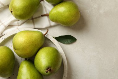 Yeşil armut tepsisi ve beyaz desenli arka planda mutfak havlusu.