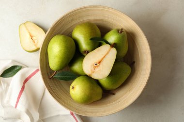Beyaz desenli arka planda yeşil armut ve mutfak havlusu olan kase.