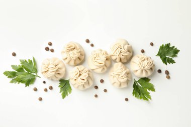 Beyaz arka planda çiğ khinkali, biber ve maydanoz.