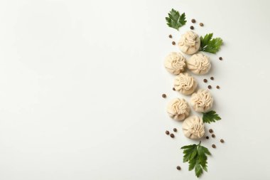 Beyaz arka planda çiğ khinkali, biber ve maydanoz.