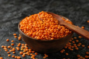 Siyah dumanlı arka planda kırmızı baklagiller olan kase ve kaşık