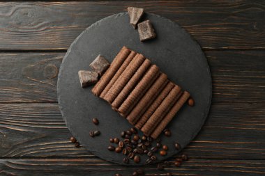 Çikolatalı gofret tepsisi, kahve çekirdekleri ve ahşap arka planda çikolata.