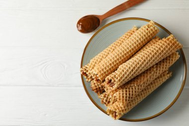 Yoğunlaştırılmış süt ve kaşık ile ahşap zemin üzerinde gofret ruloları ile tabak