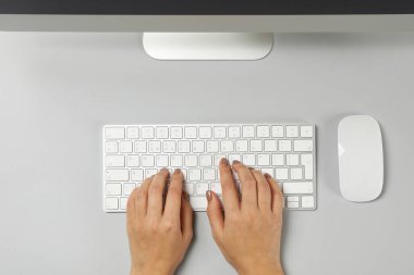 Gri masadaki masaüstü bilgisayarında çalışan kadın