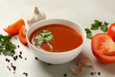 Domates çorbası ve hafif arka planda malzemelerle dolu bir kase.