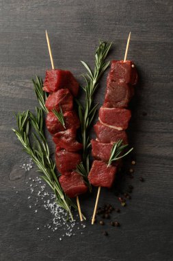 Koyu arka planda çiğ et ve baharatlı şişler.