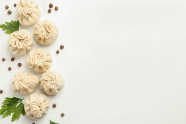 Beyaz arka planda çiğ khinkali, biber ve maydanoz.