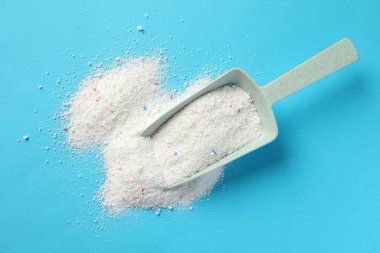 Mavi arka planda çamaşır tozu olan plastik kepçe.