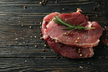 Tahta arka planda baharatlı ve otlu taze çiğ biftek.