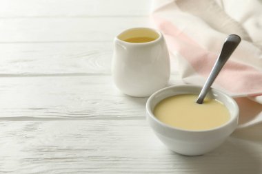 Ahşap arka planda yoğunlaştırılmış sütle mutfak havlusu ve kaseleri.