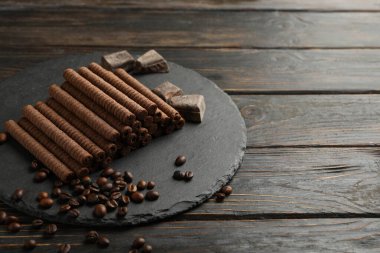 Çikolatalı gofret tepsisi, kahve çekirdekleri ve ahşap arka planda çikolata.