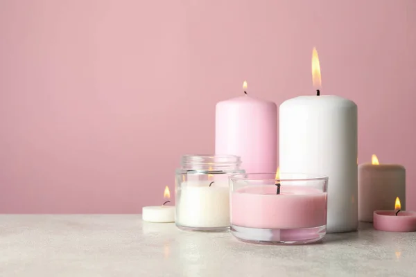 ピンクの背景に白いテーブルの上でリラックスするための香りのキャンドル — ストック写真