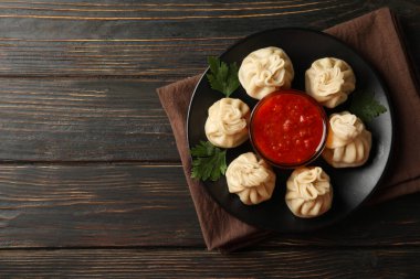 Lezzetli öğle yemeği kavramı, bir tabak khinkali ve ahşap arka planda sos.