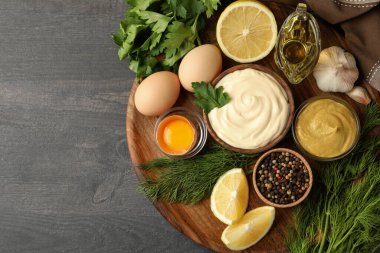 İçinde bir kase mayonez ve ahşap arka planda yemek pişirmek için malzemeler var.