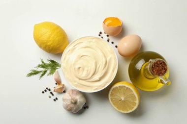 Beyaz arka planda yemek pişirmek için mayonez ve malzemelerle dolu bir kase.