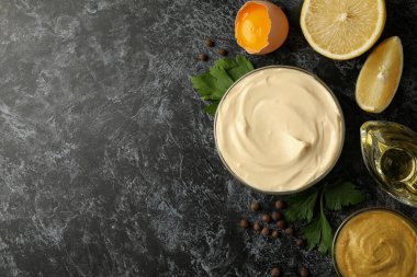 Siyah dumanlı arka planda pişirmek için mayonez ve malzemelerle dolu bir kase.