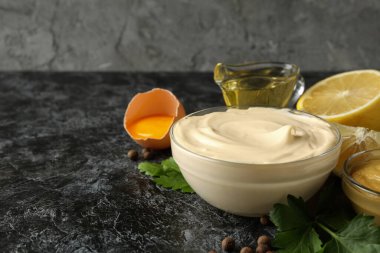 Siyah dumanlı arka planda pişirmek için mayonez ve malzemelerle dolu bir kase.