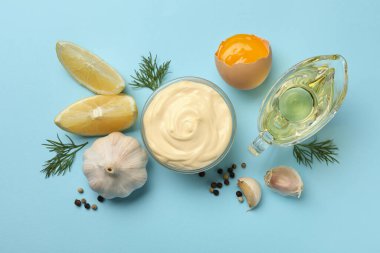 Mavi arka planda mayonez ve malzemelerle dolu bir kase.