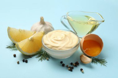 Mavi arka planda mayonez ve malzemelerle dolu bir kase.