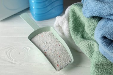 Beyaz ahşap arka planda toz, deterjan ve havlular ile kepçe