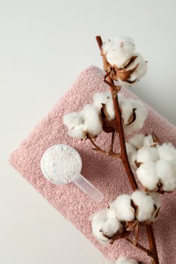 Beyaz arka planda çamaşır tozu, pamuk ve havluyla kepçe