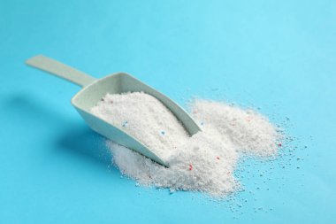 Mavi arka planda çamaşır tozu olan plastik kepçe.