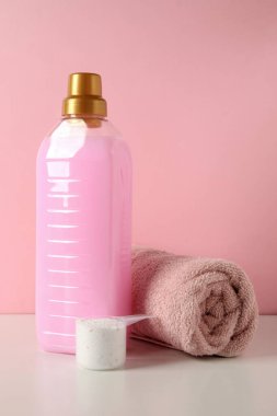 Deterjan, toz ve havlu ile kepçe beyaz masa üzerinde pembe arka plan