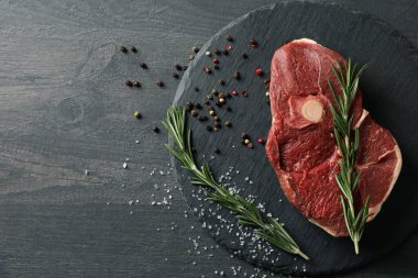 Biftek tepsisi, otlu ve ahşap arka planda baharatlı.