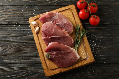 Ahşap arka planda taze çiğ biftek eti olan bir pano.