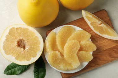 Beyaz desenli arka planda Pomelo dilimleri ile olgun pomelo ve tabak