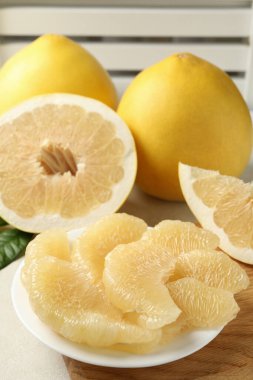 Olgun pomelo ve tabak beyaz desenli masa üzerindeki dilimlerle.