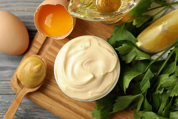 Bir kase mayonez ve ahşap arka planda yemek pişirmek için malzemeler.