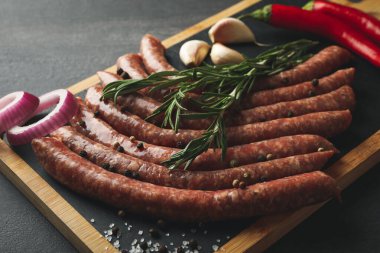 Koyu arka planda çiğ sosis, bitki ve baharatlı pano