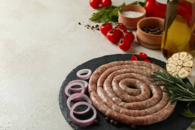 Beyaz dokulu arka planda çiğ sosis ve malzemelerle dolu tepsi