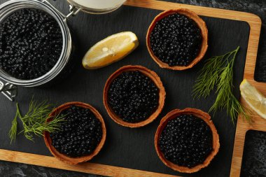 Siyah dumanlı arka planda tartlı pano ve havyarlı kavanoz, üst görünüm