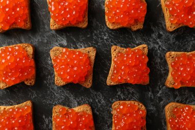 Siyah dumanlı arka planda havyar ve ekmek dilimleri ile düz yatıyordu