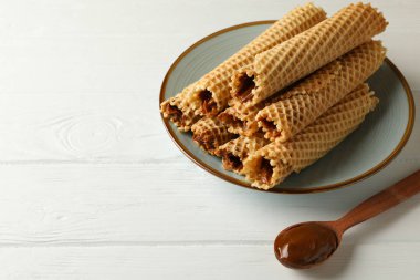 Yoğunlaştırılmış süt ve kaşık ile ahşap zemin üzerinde gofret ruloları ile tabak