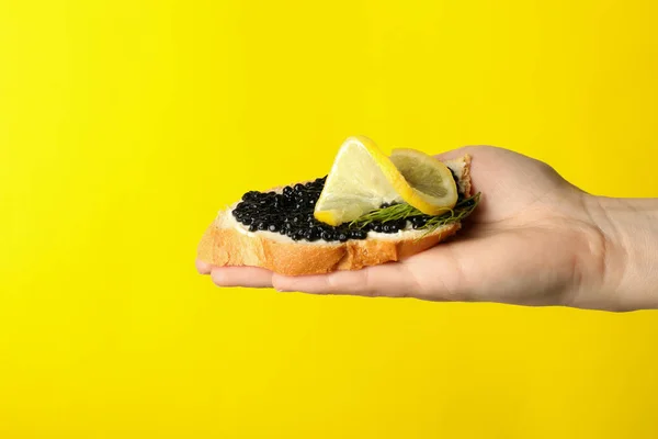 Sandwich Mano Femenina Con Caviar Negro Sobre Fondo Amarillo — Foto de Stock