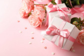 Růže a dárkové krabice na růžovém pozadí, prostor pro text