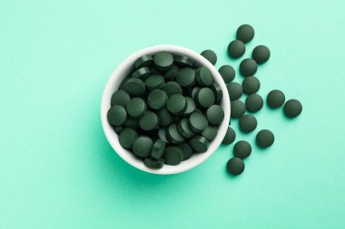 Arka planda spirulina hapları olan bir kase.